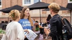 A student wearing a 'Heels Abroad' shirt discusses studying abroad with students.